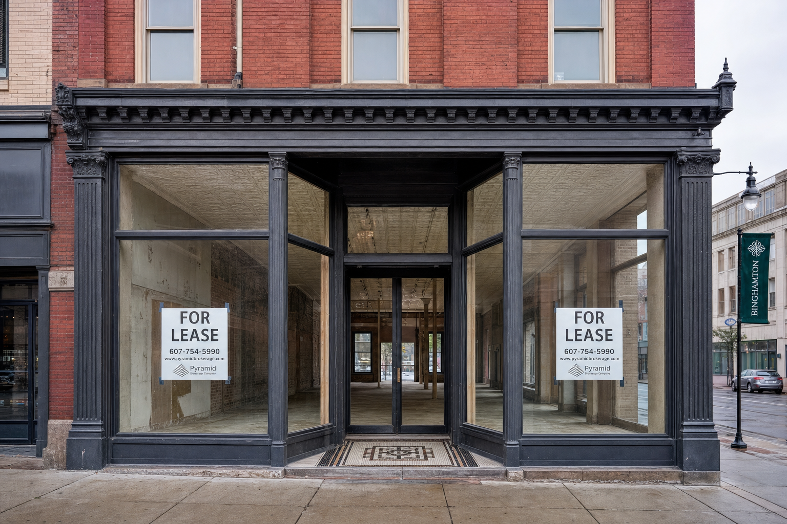 Vacant historic storefront in downtown Binghamton with large display windows and tin ceiling.